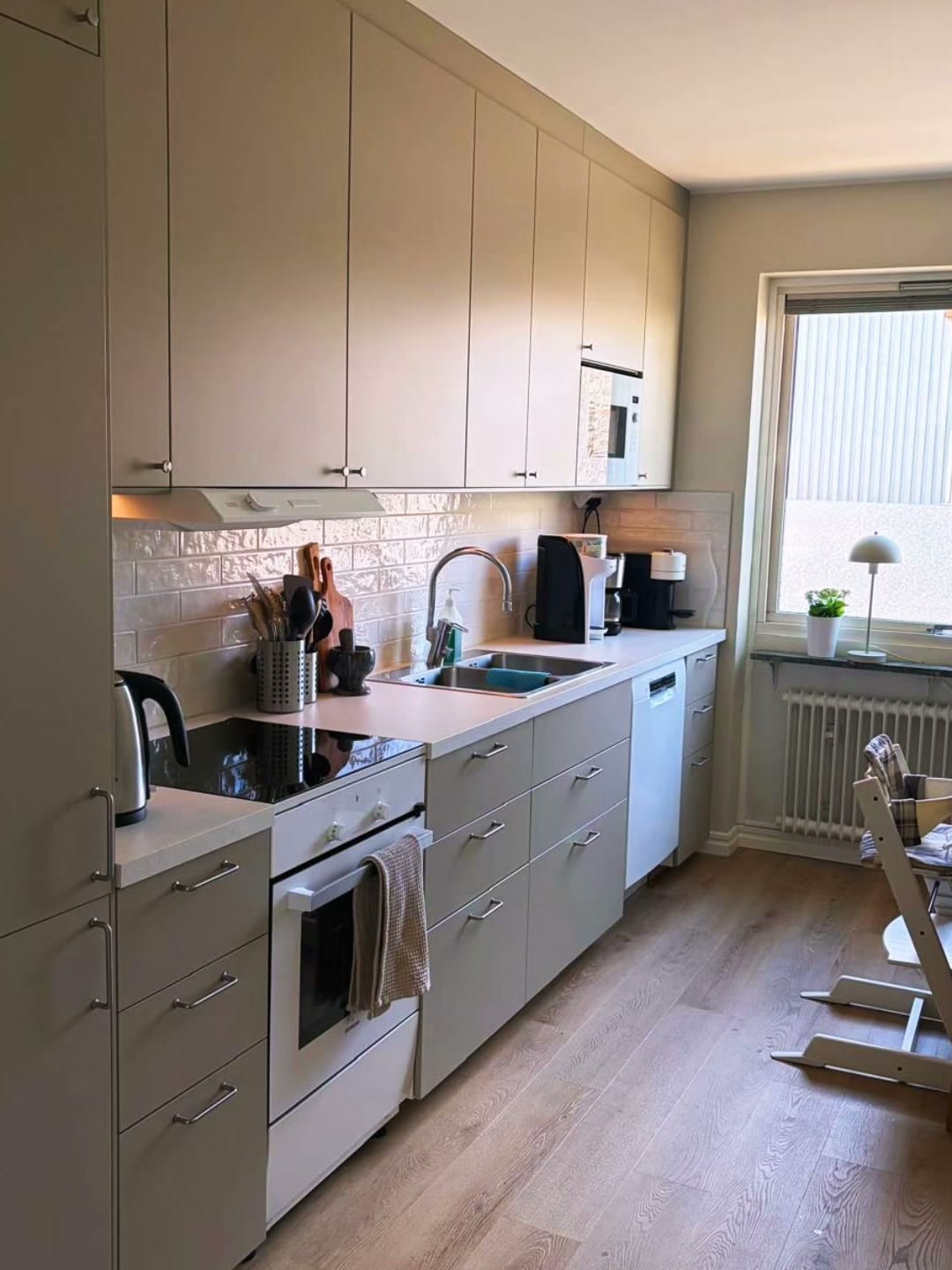 Nymonterat kök med beige luckor, kaklat stänkskydd och nya vitvaror