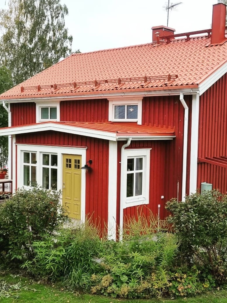 Faluröd villa med nybyggd tillbyggnad och gul ytterdörr